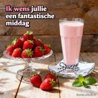 Aardbeien op glazen schaal en een glas aardbeienshake op houten tafel, met tekstwens