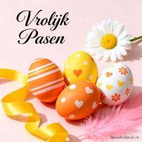 Paasgroet met drie versierde eieren, gele linten, een madeliefje en roze veer op pastelroze achtergrond